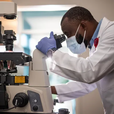 Masked Man Using a microscope